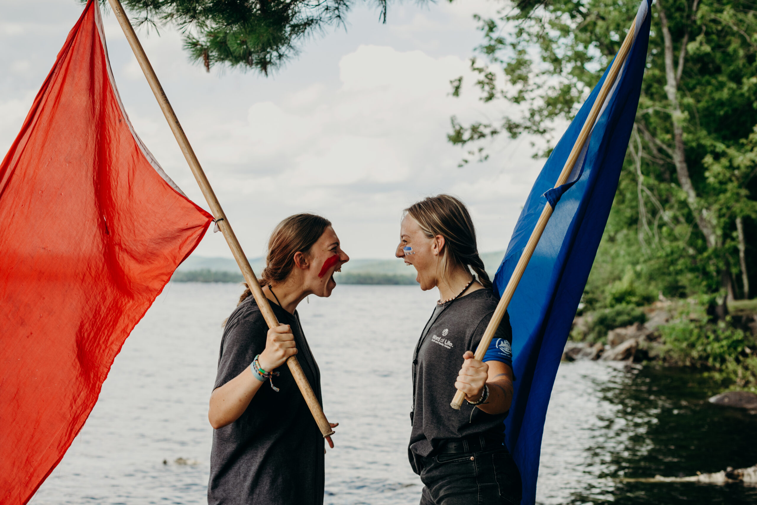 Two women yelling at each other while holding red and blue flags
